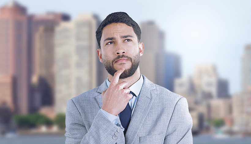 A man in a light gray suit stands outdoors in front of a blurred city skyline, looking upward with a thoughtful expression and his hand resting on his chin.
