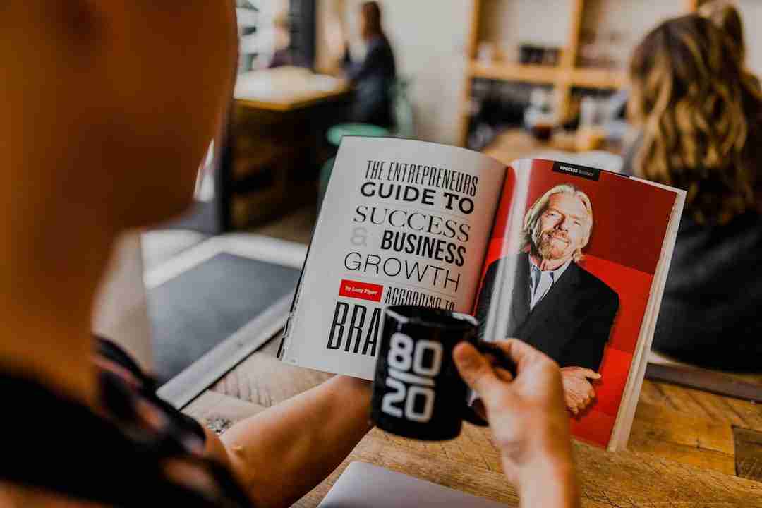 A person holds a black mug and reads a business magazine featuring an article titled "The Entrepreneur's Guide to Success & Business Growth" with a photo of a man in a suit on the right page.